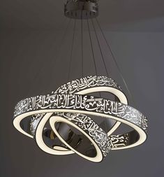 a chandelier hanging from the ceiling with arabic calligraphy written in white on it