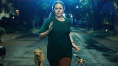 a woman walking two dogs on a street at night with trees in the back ground