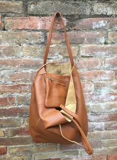 Large tote leather bag in dark CAMEL BROWN. Saddle brown shoulder bag. Tan color natural GENUINE leather. Large enough for books or a laptop, tablet, cosmetics bag etc. Leather shopper. The inside of the bag is not lined (although properly finished!) . We added a small leather pouch on the inner part of the bag (4th pic) The bag can be closed by 2 leather straps attached to each side. Excellent quality soft but strong genuine leather. Width upper part: 41cm - 16 inch Height: 38 cm - 15 inch This Versatile Brown Bucket Bag For On-the-go, Brown Large Capacity Laptop Bag For On-the-go, Versatile Cognac Leather Bag, Large Capacity Brown Leather Bag, Versatile Cognac Leather Shoulder Bag, Casual Cognac Bag With Leather Handles, Brown Everyday Laptop Backpack, Light Brown Leather-handled Bucket Tote Bag, Light Brown Hobo Bag With Leather Handles For Shopping