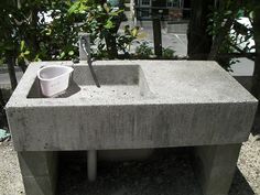 a concrete sink sitting on top of a cement slab next to trees and shrubbery