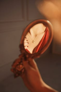 a woman's hand holding a magnifying glass with a necklace on it