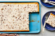 a blue tray topped with a piece of cake covered in white frosting