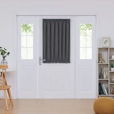 a living room filled with furniture and a white book shelf next to a door covered in curtains