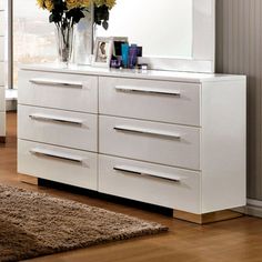 a white dresser sitting next to a window filled with yellow flowers and a mirror on top of it