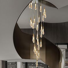 a modern chandelier hanging from the ceiling in a room with stairs and windows