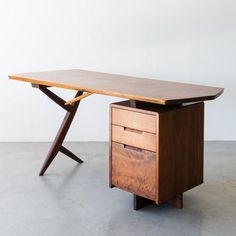 a wooden desk with two drawers underneath it and a white wall in the back ground