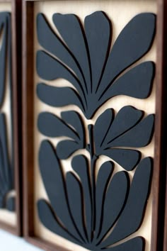 three wooden panels with black leaves on them