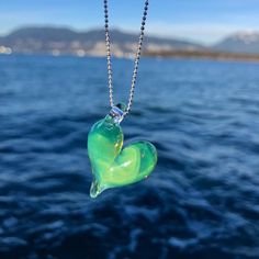 "One-of-a-kind ocean inspired heart necklace in a gorgeous and iridescent Sea Slyme green borosilicate glass. Definitely the most versatile wearable piece in the glasea collection. The colour sparkles even more with brighter colours. Approximately 1\" x 1\" Pendant comes with a sterling silver stamped 925, 1 mm snake or ball chain. Please select your length at check out.  Sterling Silver chains are made in Italy.  Each piece is completely handmade and is one of a kind. Therefore, sizes are approximate and design is unique and therefore might vary slightly from the photos. Thanks for supporting my art  All pieces are hand made in my studio in Vancouver, BC, Canada" Green Heart Necklace For Gift, Green Heart Beads Necklace As Gift, Handmade Green Heart Necklace As Gift, Green Heart Pendant Necklace As Gift, Handmade Green Heart Cut Jewelry, Handmade Iridescent Jewelry For Valentine's Day, Green Heart Charm Necklace For Valentine's Day, Green Heart Pendant Necklace Gift, Handmade Green Heart Necklace