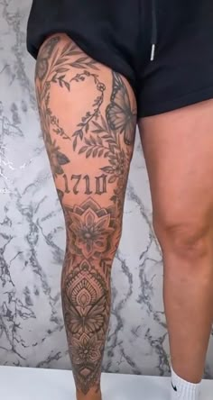 a woman's legs with tattoos on them and flowers in the bottom right leg