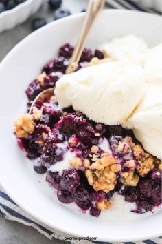 blueberry cobbler with ice cream on top in a white bowl, ready to be eaten