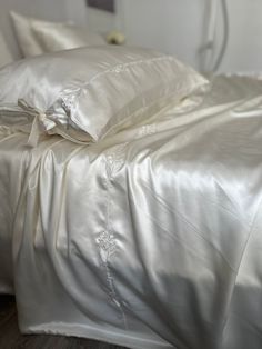 an unmade bed with white sheets and pillows