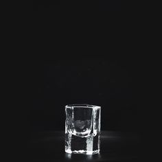 an empty glass sitting on top of a black table next to a white object in the dark