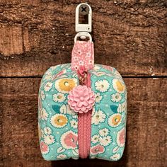 a blue and pink flowered purse hanging on a wooden wall with a metal hook