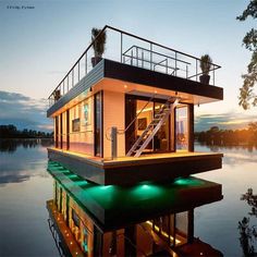 a houseboat floating on top of a body of water at night with green lights