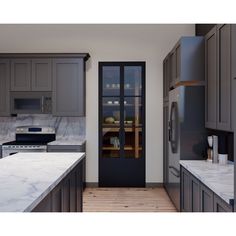 a kitchen with gray cabinets and marble counter tops, along with an open glass door leading to the dining room