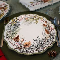 a place setting with pine cones and berries