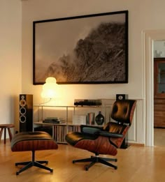 an empty living room with a large painting on the wall and two chairs in front of it