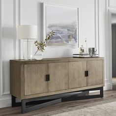 a sideboard with two doors and a vase on top in a living room area