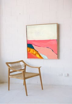 a chair sitting in front of a painting on the wall