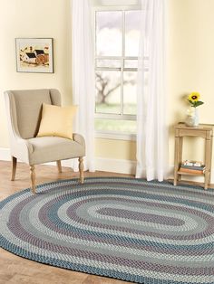 a living room with a chair and rug in front of a window on the floor