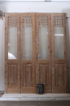 an old wooden door with glass panels on the front and side doors, in a white room