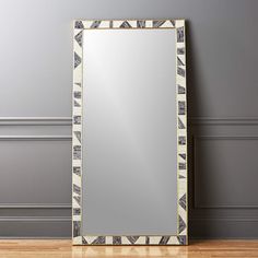 a mirror sitting on top of a hard wood floor next to a gray wall and wooden floor