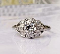 an old - fashioned diamond ring sits on a white surface