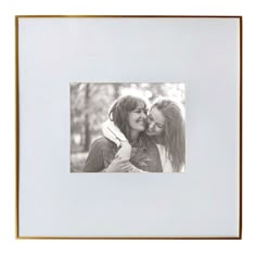 two women are hugging each other in front of a white background with gold trimming