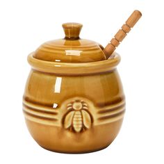 a ceramic honey jar with a wooden spoon in the lid and a bee on it