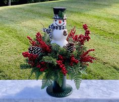 a vase filled with red berries and a snowman sitting on top of a table