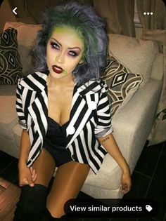 a woman sitting on top of a couch wearing a black and white striped jacket with green hair