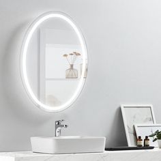 a white sink sitting under a round mirror next to a wall mounted faucet