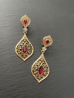 These are lovely dangling chandelier style earrings in gold .an vintage style gold  teardrop dangle earrings with garnet red stones in the middle  These are an Indian earrings that could be worn by both traditional and an western attire. Note: The product shipped will be same as shown in the picture however, actual colours may vary slightly from those shown due to lighting in the photography. Pls note The shades of gold / silver  may vary slightly. We do not accept any returns or refunds.However in case of any issue we will definitely try and resolve it! Festival Jeweled Drop Earrings, Jeweled Drop Chandelier Earrings For Festivals, Festival Gold Ruby Chandelier Earrings, Festival Ruby Chandelier Earrings In Gold, Gold Ruby Chandelier Earrings For Festivals, Teardrop Jewelry With Intricate Design For Party, Elegant Metal Teardrop Danglers, Teardrop Party Jewelry With Intricate Design, Elegant Festive Clip-on Earrings