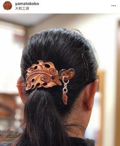 a woman with a hair clip in the shape of a dragon on her back is seen from behind