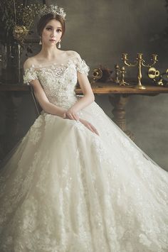 a woman in a white wedding dress sitting on a chair wearing a tiara and earrings