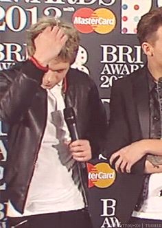 two men standing next to each other on a red carpet with microphones in front of them