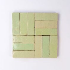 small square tiles in light green and cream colors on a white surface, arranged as squares