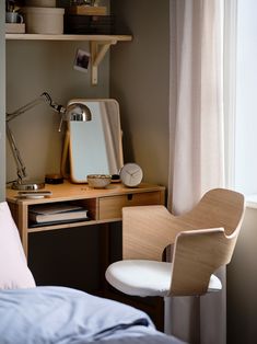 a bedroom with a desk and chair next to a window in front of the bed