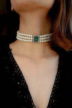 This stunner of a piece is an absolute show stealer. It features a green stone at the center and is lined with faux diamonds. The strings are strewn with shell pearls and accentuate the appeal of the centerpiece. Closure - Lobster. There's a subtle yet clearly indisputable quality in our traditional attires that brings out the depth of a woman's femininity. The warm glory of the gold, the ritualistic richness of red and green, the clamor of payals and kadas, are a celebration of womanhood. The m Formal Jeweled Choker Jewelry, Formal Rhinestone Choker Jewelry, Elegant Jeweled Diamond White Jewelry, Elegant Diamond Jeweled Jewelry, Elegant Crystal Jewelry With Gemstone Accents, Elegant Diamond White Jeweled Jewelry, Exquisite Green Jewelry With Stones, Formal Emerald Jewelry With Stones, Elegant Jeweled Choker For Formal Occasions