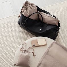 a black bag sitting on top of a white floor next to a purse and cell phone