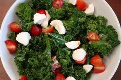 a white bowl filled with lots of veggies on top of a wooden table