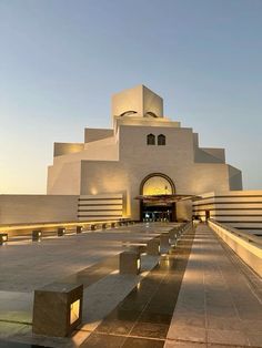 a large building that has some benches in front of it and lights on the side