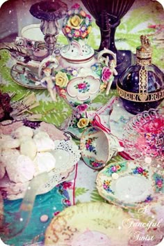 a table topped with plates and cups filled with teapots next to each other