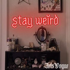 a red neon sign that says stay weird above a shelf with various items on it