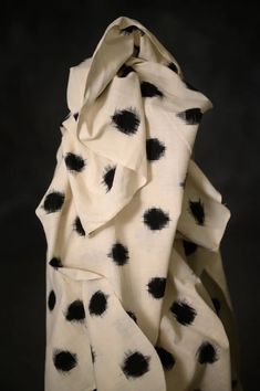 a black and white polka dot print fabric on a dark background, with an uneven pattern