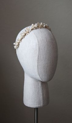 a white headpiece with pearls on it's side, sitting on top of a mannequin