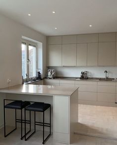 an empty kitchen with two stools in front of the counter top and sink area