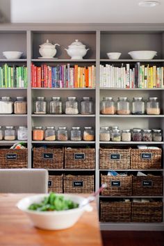 a wooden table topped with lots of baskets filled with food next to bookshelves