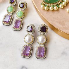 Look ravishing and take your love for long dangle earrings to another level! Gorgeous pair of earrings luxuriously studded with amethyst, pearl and CZ stones - perfect to wear them in your favorite fancy events to make all eyes rest on you. Approximate earrings length is 3.2". Designed over high-quality brass as base metal with silver and gold plating. Made by order. Kindly allow 4-6 weeks for the delivery of this item. For custom or urgent requests, please contact support@alacouture.com. *Please Note: We use faux stones and beads in all of our jewelry Unique Gift Cards, Long Dangle Earrings, Faux Stone, All Eyes, Green Stone, All About Eyes, Cz Stone, Silver And Gold, Free Giveaway