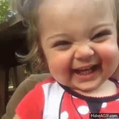 a smiling baby wearing a red and white shirt with polka dots on it's chest